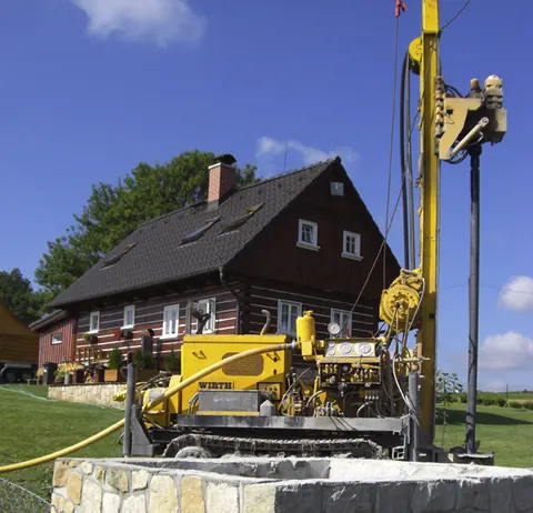 Vrtná souprava při vrtání studny u roubené chalupy